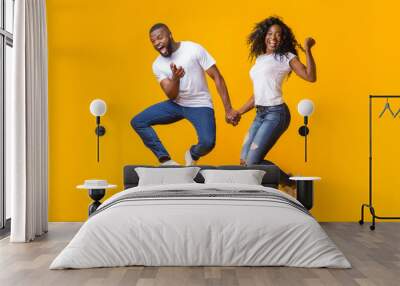 Joyful african couple having fun over yellow background Wall mural