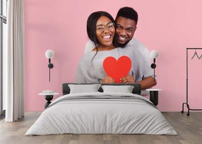 Joyful african couple holding big red heart together Wall mural