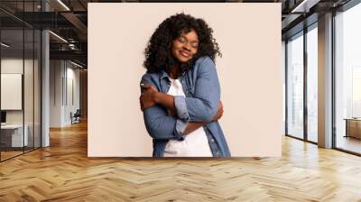 Joyful black lady in love hugging herself Wall mural