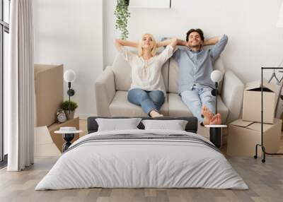 Joyful Husband And Wife Relaxing On Couch In New Home Wall mural