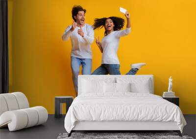 Joyful interracial couple taking selfie while jumping, having fun together Wall mural