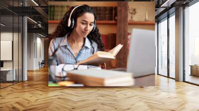 Lady sitting at desk, wearing headset, using computer, reading book Wall mural