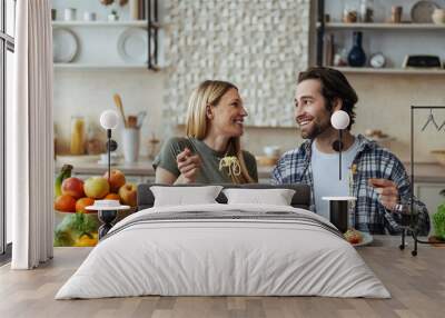 Laughing happy european millennial blond wife and hasband with stubble eating pasta Wall mural