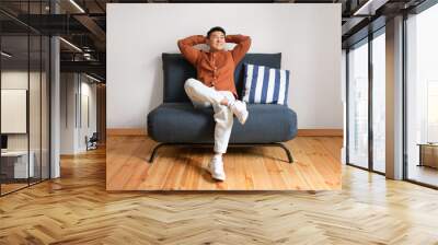 Lazy weekend. Happy mature asian man relaxing with hands behind head, sitting on sofa over white wall Wall mural