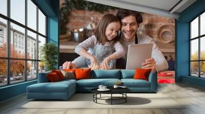 Little Girl And Her Dad Checking Recipe On Digital Tablet While Baking Wall mural