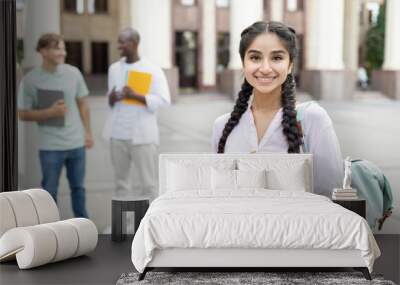 Loans for education concept. Portrait of happy indian female student posing outdoors in campus with her classmates Wall mural