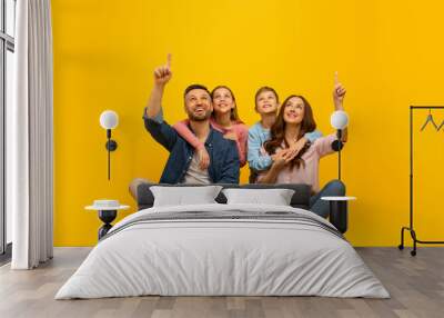 Look There. Parents With Two Kids Sitting On Floor And Pointing Up Wall mural