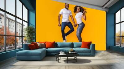 Lovely afro couple is jumping hand in hand Wall mural