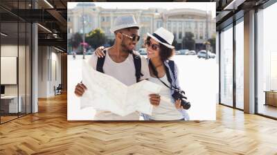 Loving african-american couple traveling and reading map in city Wall mural