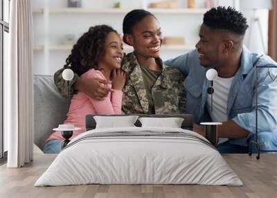 Loving black woman in camouflage uniform having conversation with family Wall mural