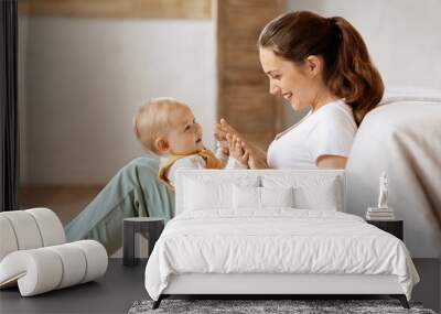 Loving young mother caressing her cute baby boy, home interior Wall mural