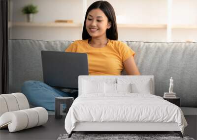 Loyal dog resting by its female owner using laptop Wall mural