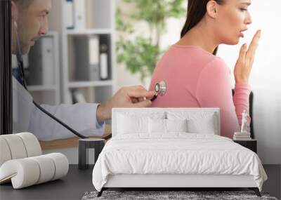 Male doctor checking breath of female patient Wall mural