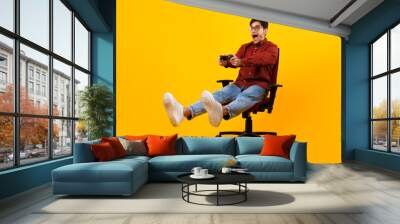 Male Gamer Shouting Playing Videogame Sitting In Chair, Yellow Background Wall mural