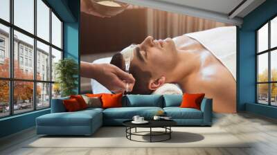 Man getting face mask by beautician at spa Wall mural