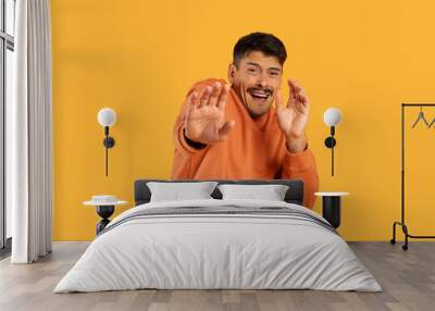 Man in Orange Shirt Making Hand Gesture Wall mural