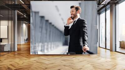 Man in suit having phone conversation while waiting for flight Wall mural