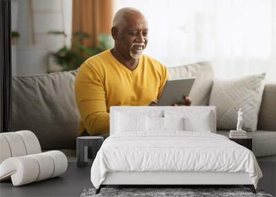 Mature African American Man Using Digital Tablet Sitting At Home Wall mural