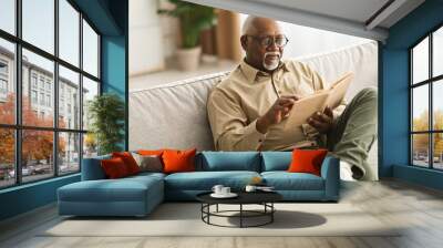 Mature Black Man Reading A Book Relaxing Sitting At Home Wall mural