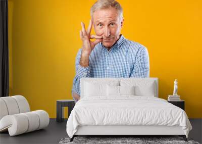 Mature man puting finger on his lips, making silence sign Wall mural