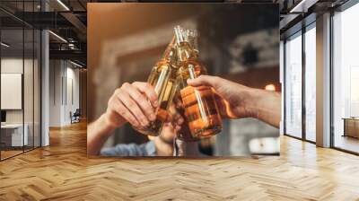 Men clinking bottles of beer together in bar Wall mural