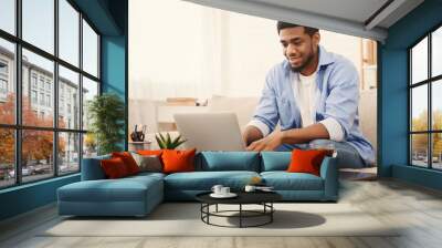 Millennial black man working on laptop in home office Wall mural