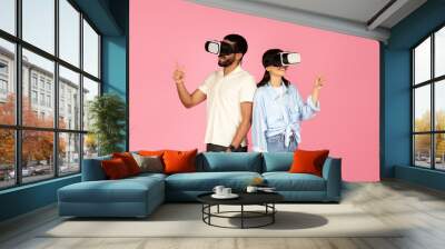 Millennial couple enjoying virtual reality experience, pink background Wall mural