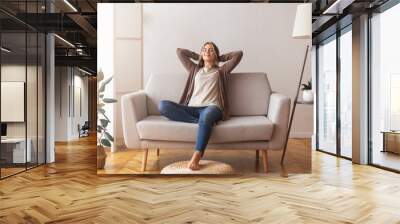 Millennial girl relaxing at home on couch, enjoying free time Wall mural