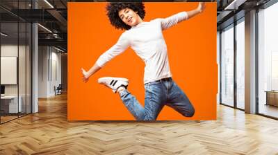 Modern hip-hop style man jumping on orange background Wall mural