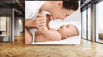 Mother playing with her baby in bedroom. Wall mural