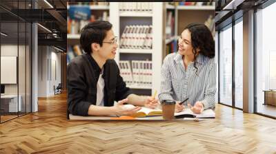 Multicultural couple sharing ideas in modern library Wall mural