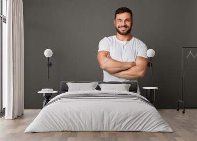 Muscular young man standing with his arms crossed Wall mural