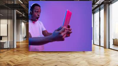 Online Offer. Shocked Black Guy Looking At Digital Tablet, Neon Lighting Wall mural