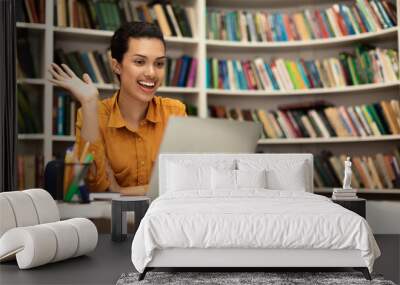 Overjoyed female teacher having online class using laptop and waving hand at webcamera, panorama with free space Wall mural