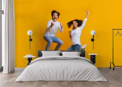 Overjoyed multiracial couple jumping in the air and celebrating success Wall mural