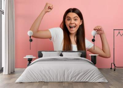 Overjoyed teen girl celebrating success, shaking fists and looking at camera Wall mural