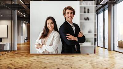 Partnership concept. Successful european man and latin woman standing with arms crossed and smiling, office interior Wall mural