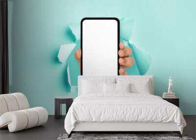 Person showing white empty smartphone screen breaking through paper Wall mural