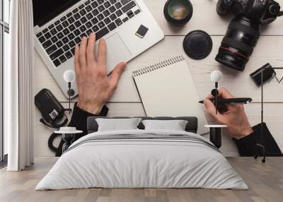 Photographer taking notes while using laptop Wall mural