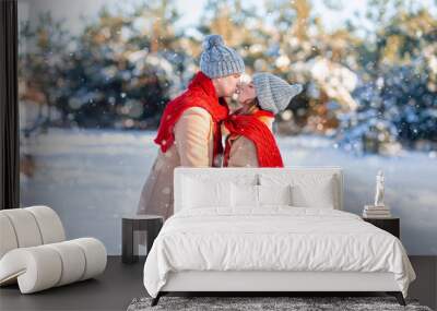 Playful man and woman kissing while walking by winter park Wall mural