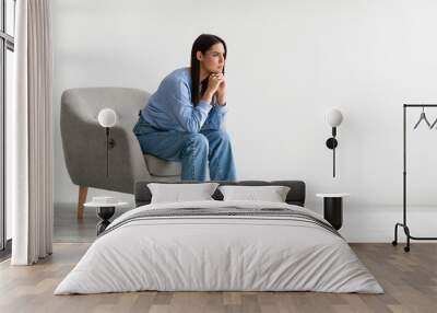 portrait of annoyed young lady sitting in armchair against white studio wall, banner design with fre Wall mural