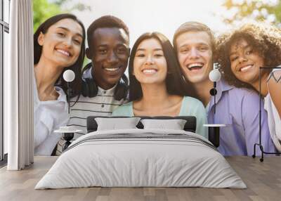 Portrait of cheerful interracial teen friends posing at camera outdoors Wall mural