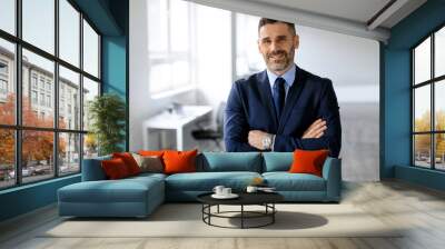 Portrait of confident middle aged male entrepreneur standing with folded arms and smiling at camera, posing in office Wall mural