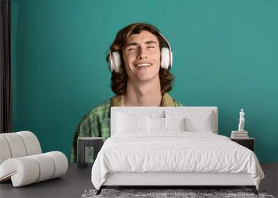 Portrait of cool teenager in headset relaxing to his favorite music on color background Wall mural