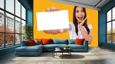 Portrait of excited young Caucasian woman holding blank white paper card with mockup for your business information Wall mural