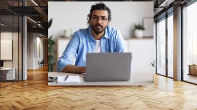 Portrait Of Handsome Young Arab Freelancer Guy Sitting At Desk With Laptop Wall mural