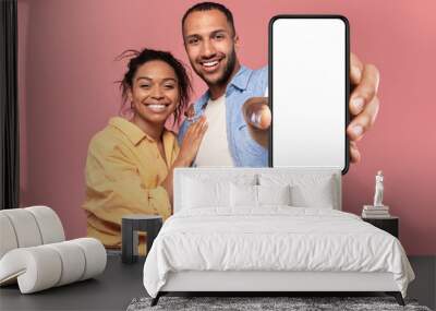 Portrait of happy african american couple presenting cellphone with mockup, promoting app or website Wall mural