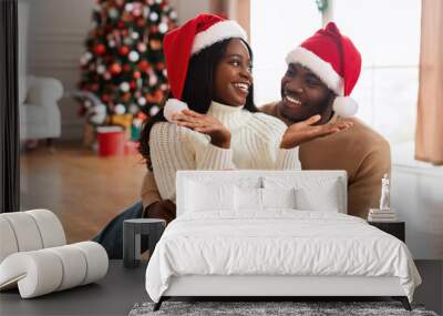 Portrait of happy black family celebrating Christmas giving present Wall mural