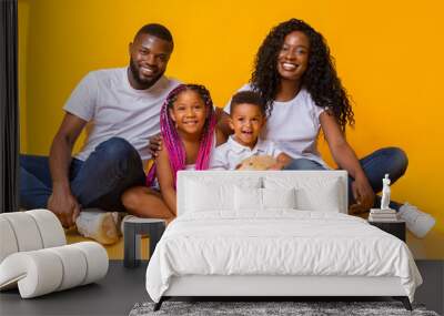 Portrait of happy family with two children over yellow background Wall mural