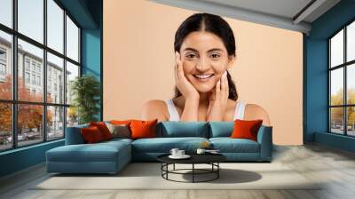 Portrait of joyful indian woman in white top touching cheeks with hands Wall mural